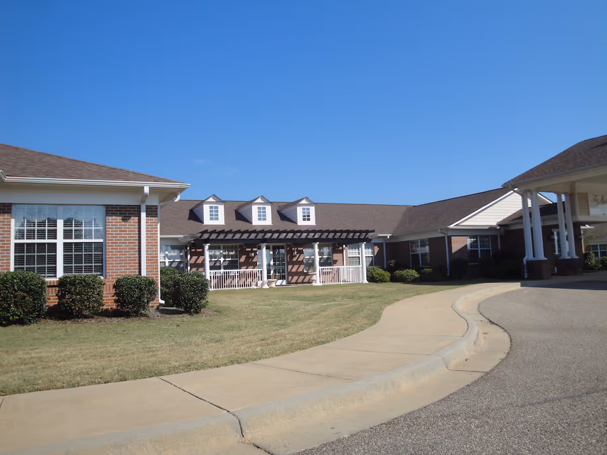 Exterior view of a brick senior living facility with a curved driveway and lawn.