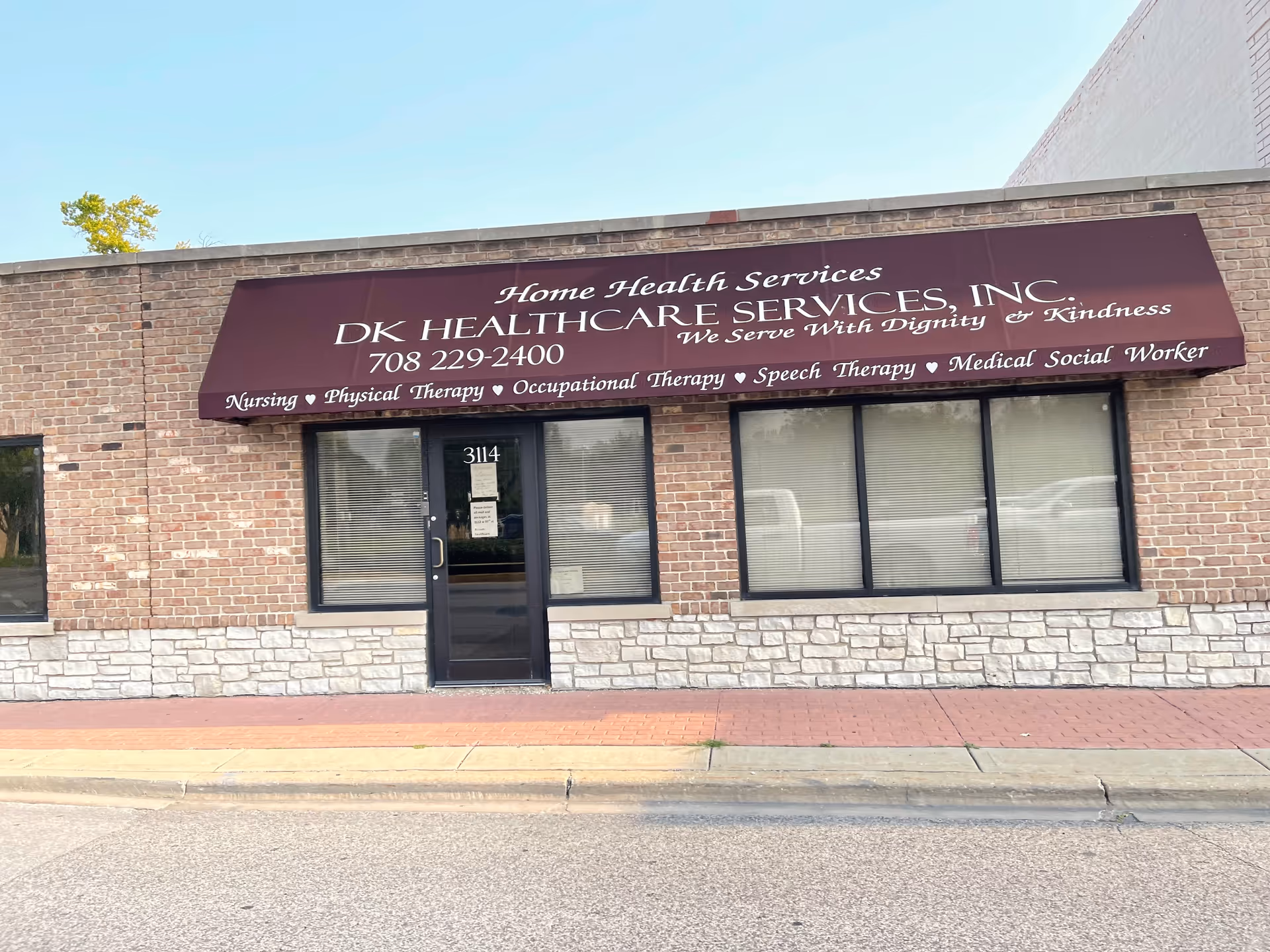 Brick building storefront with maroon awning signage for DK Healthcare Services, Home Health