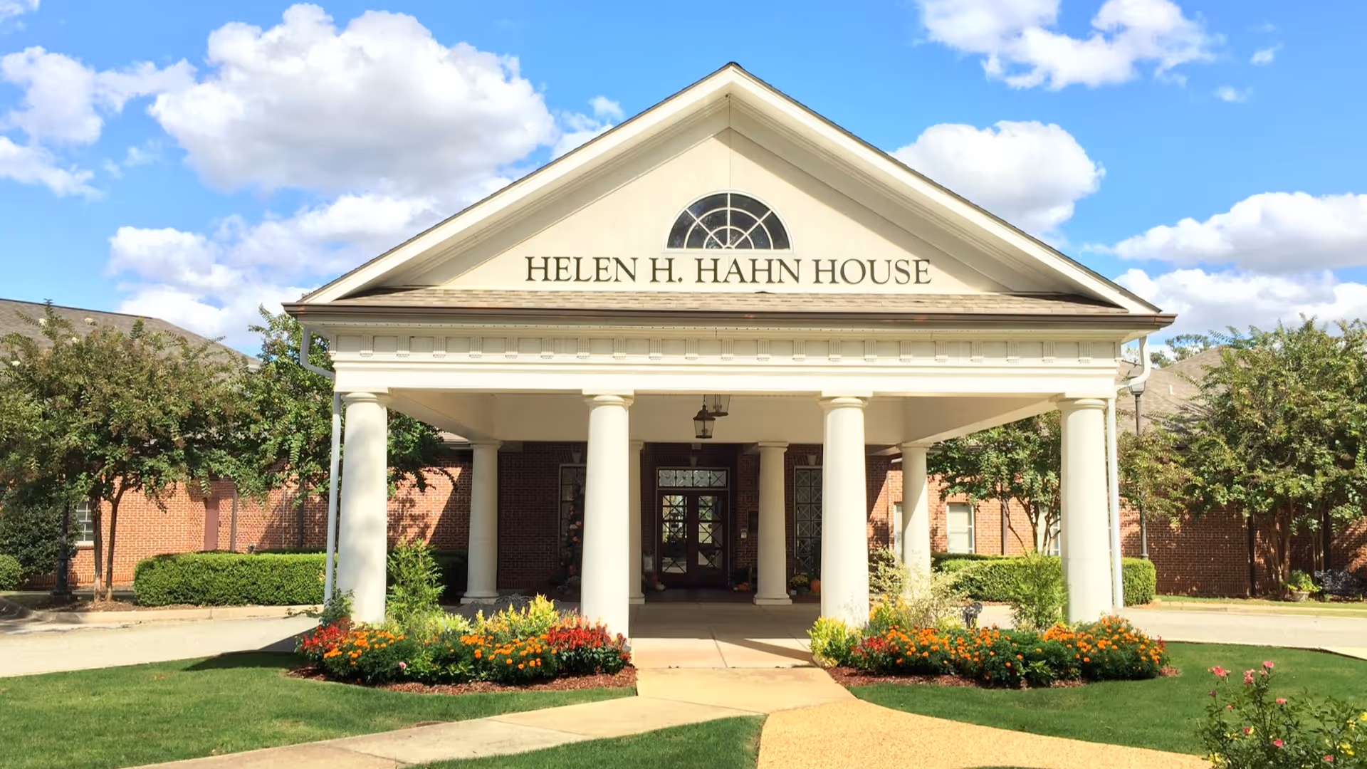 Front view of the Helen H. Hahn House Hospice with columns and landscaped entrance.