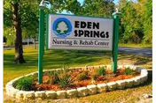 Outdoor sign for Eden Springs Nursing and Rehab Center, bordered by a landscaped flower bed.