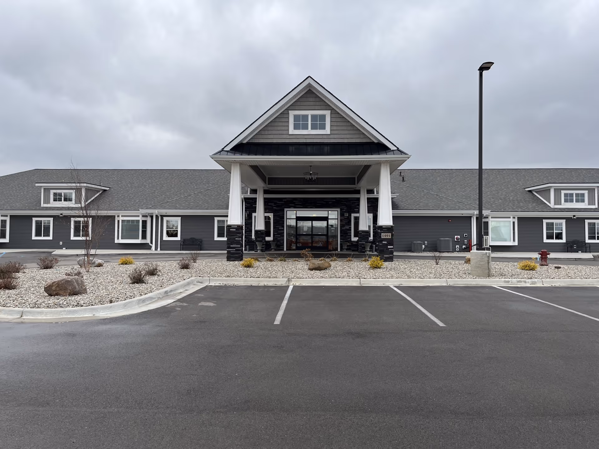 Front exterior of Hampton Manor of Madison with a covered entrance and parking lot.