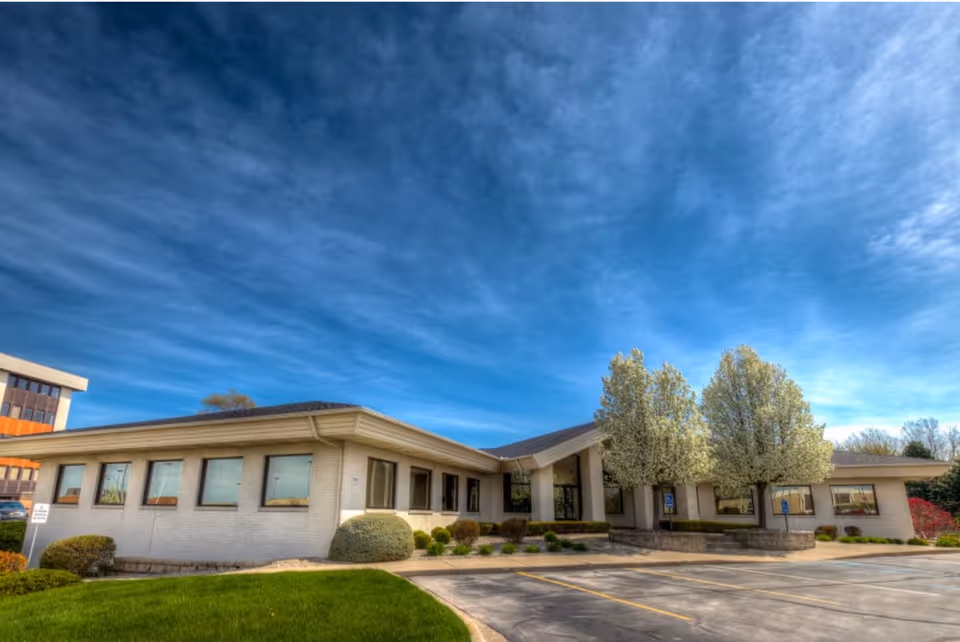Exterior view of Optimal Care senior facility with parking lot and blue sky.