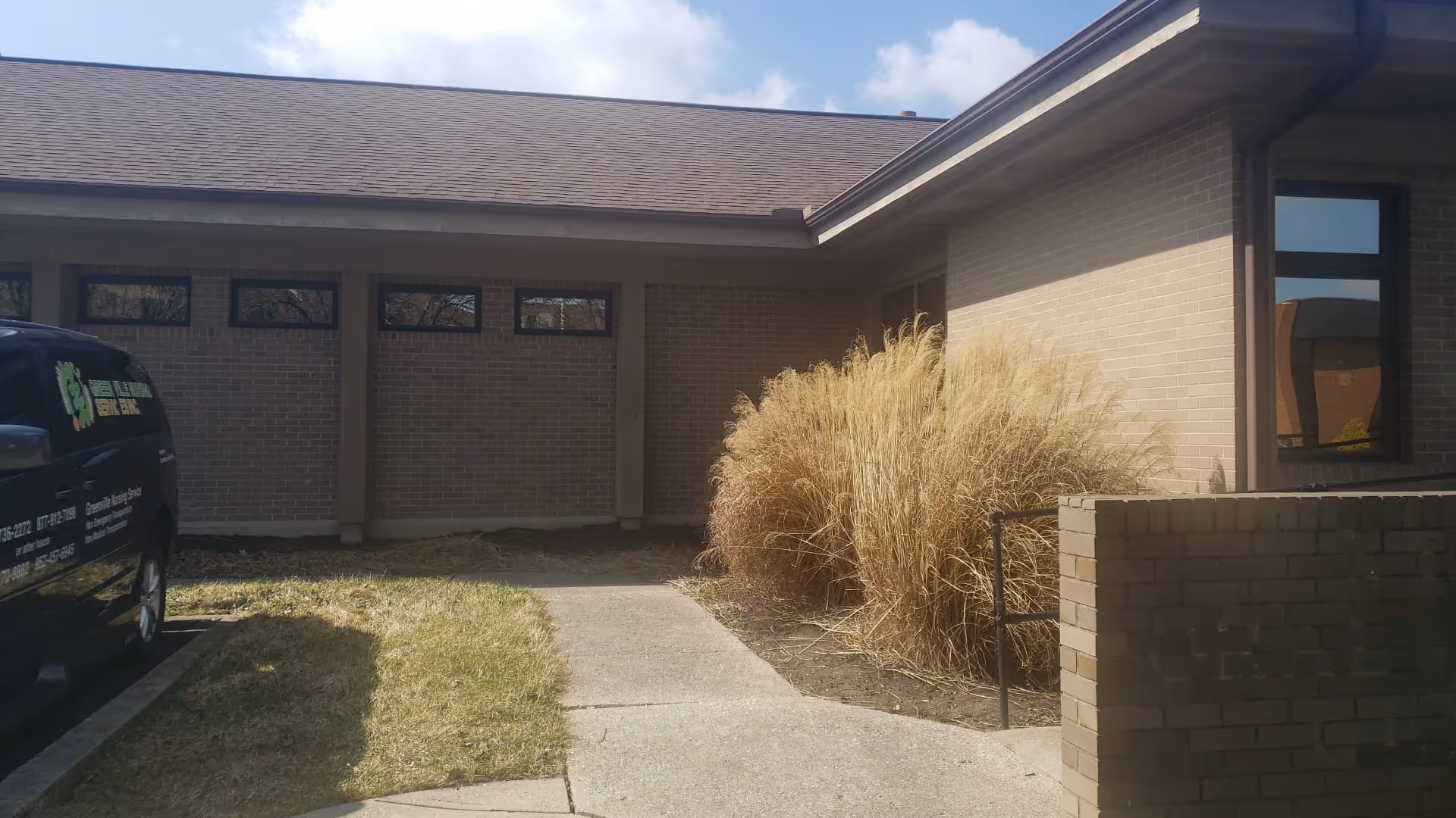 Exterior view of Greenville Nursing Services Inc building with driveway and ornamental grasses.