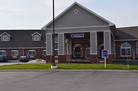 Front view of Greenwood Meadows senior living center entrance with brick facade and parking lot