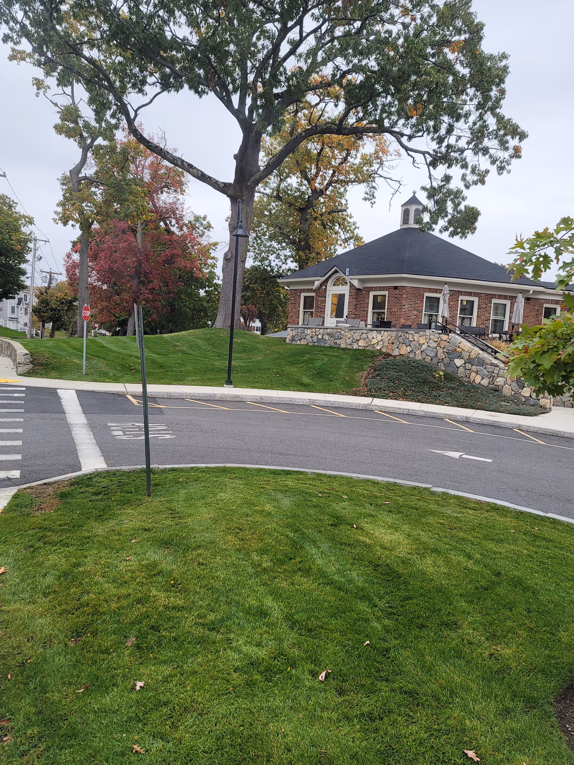 Exterior view of a brick senior living facility with stone foundation and trees.