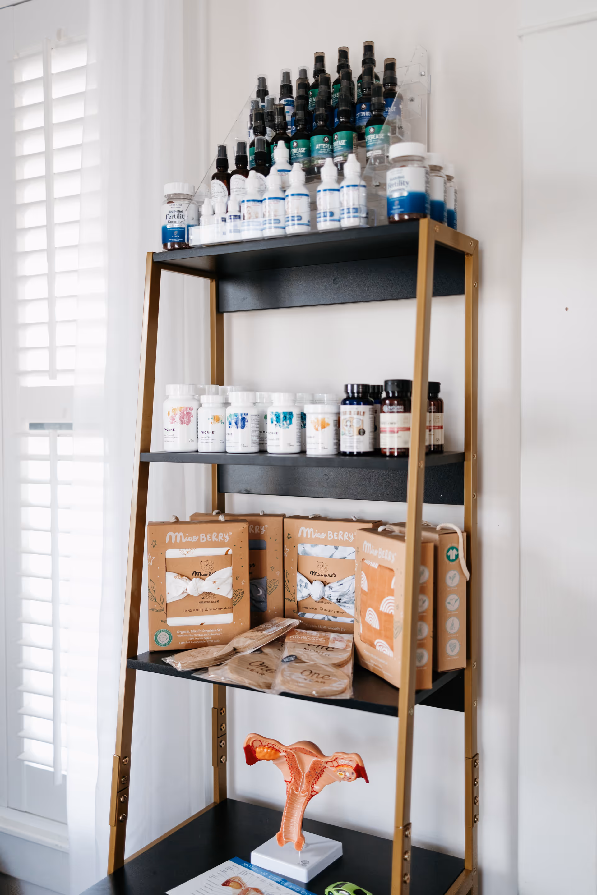Tall black-and-gold shelving holds vitamins and supplement bottles in a bright interior.
