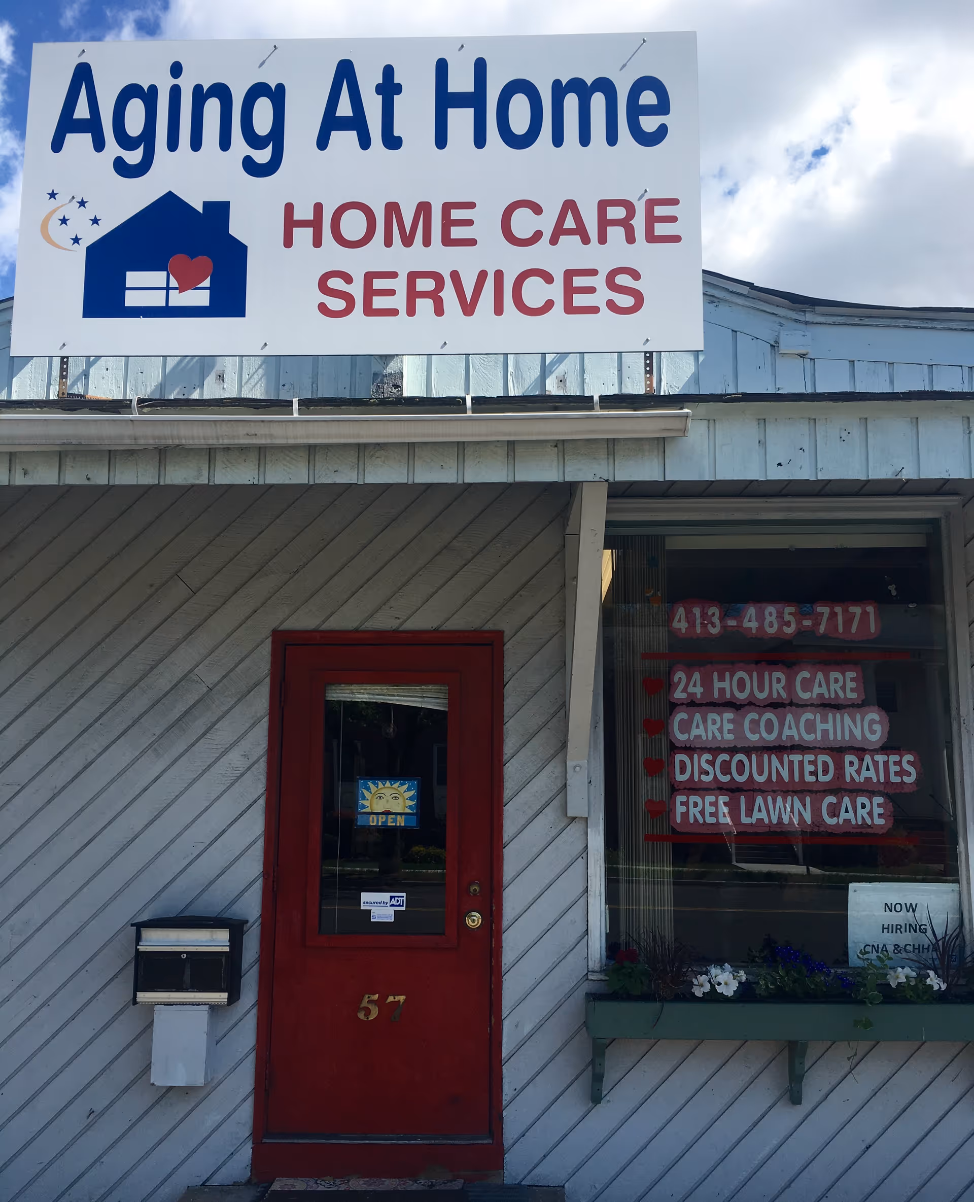 Exterior storefront showing Aging At Home sign, red entry door, and service window.