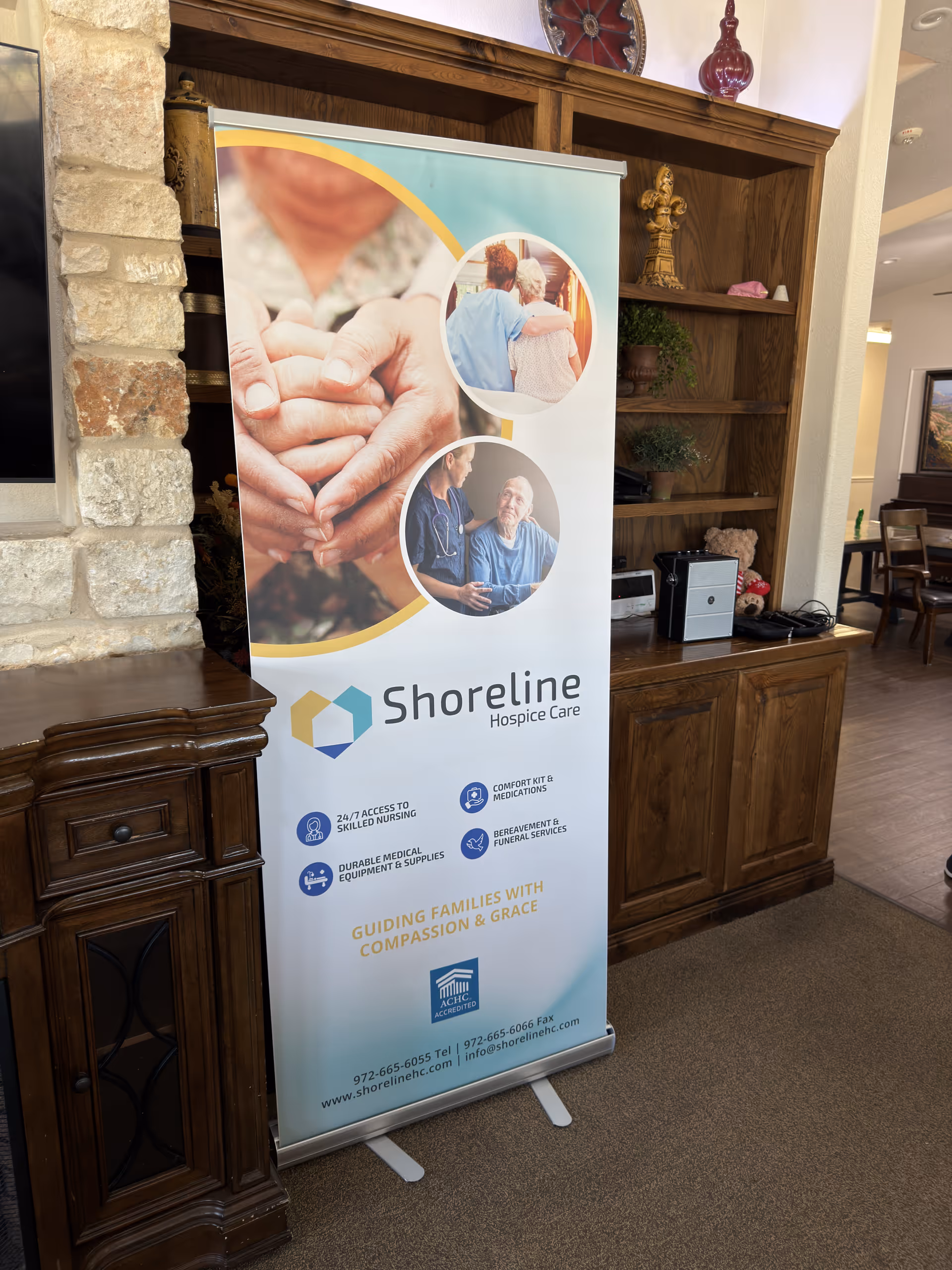 Indoor lobby with a Shoreline Hospice Care banner beside a wooden cabinet and stone wall.