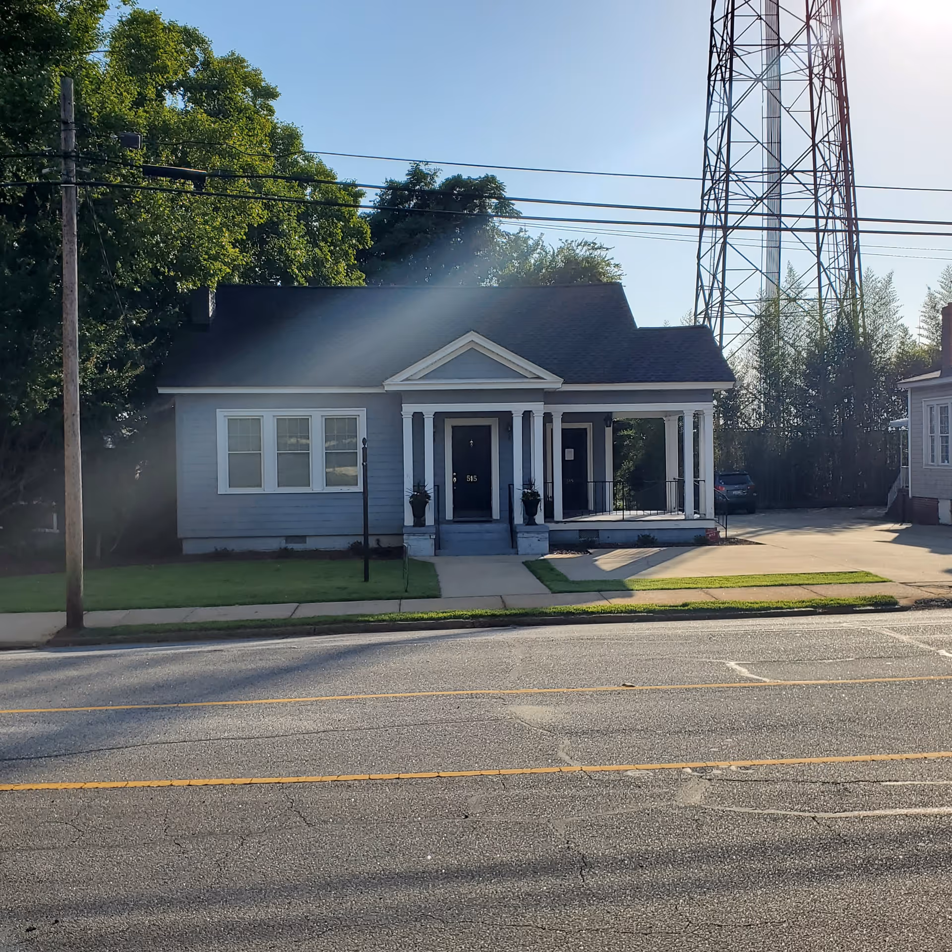 Front view of a small blue-gray house with a covered porch.