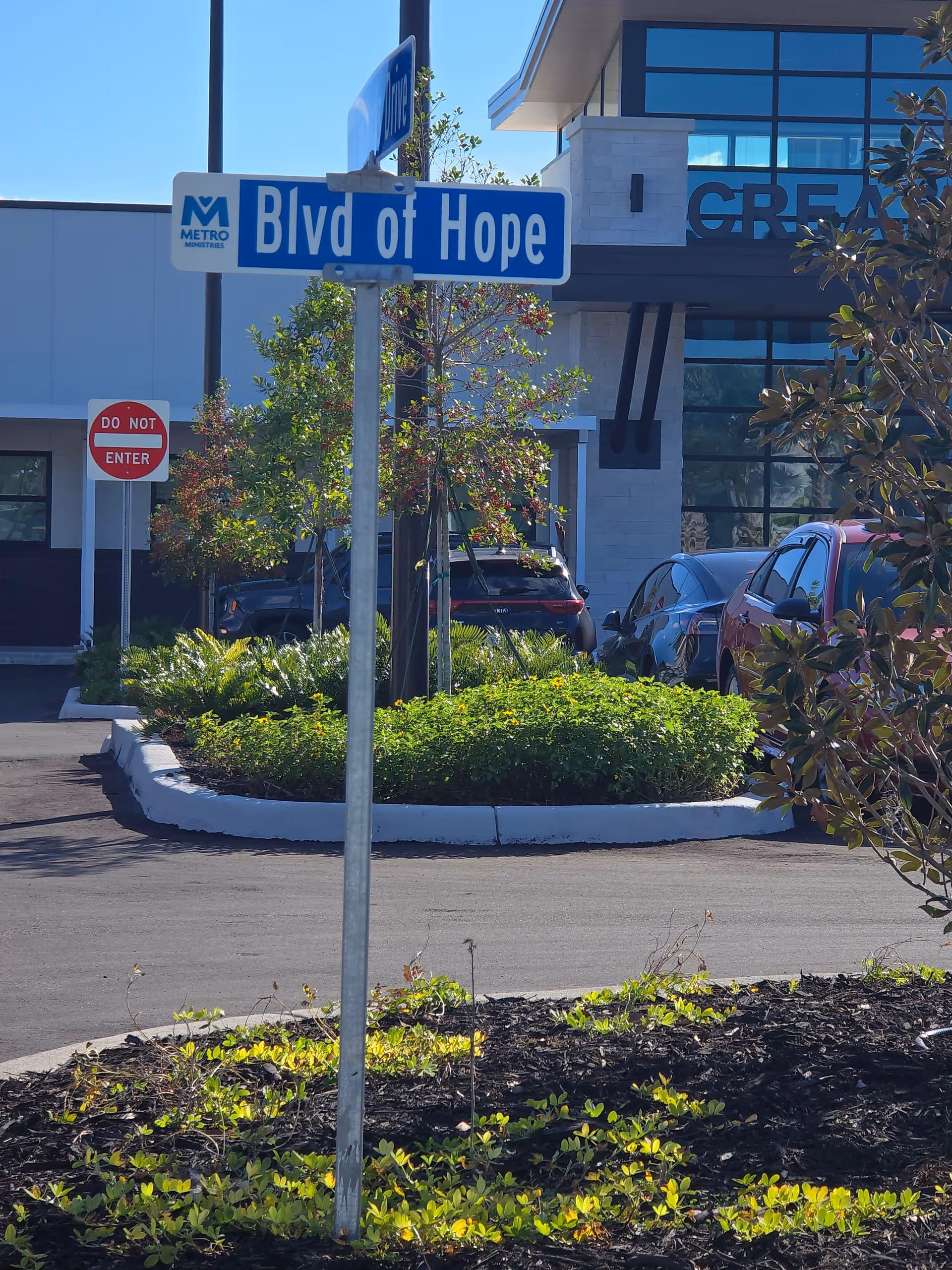 Blue Blvd of Hope street sign in front of a modern building and cars