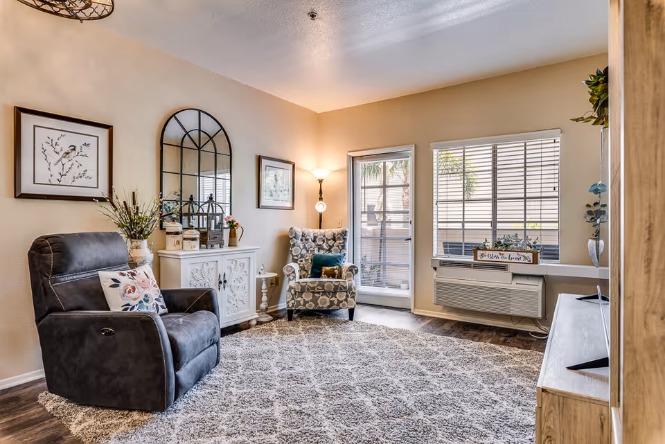 Cozy living area with two armchairs, rug, decor, and a large window.