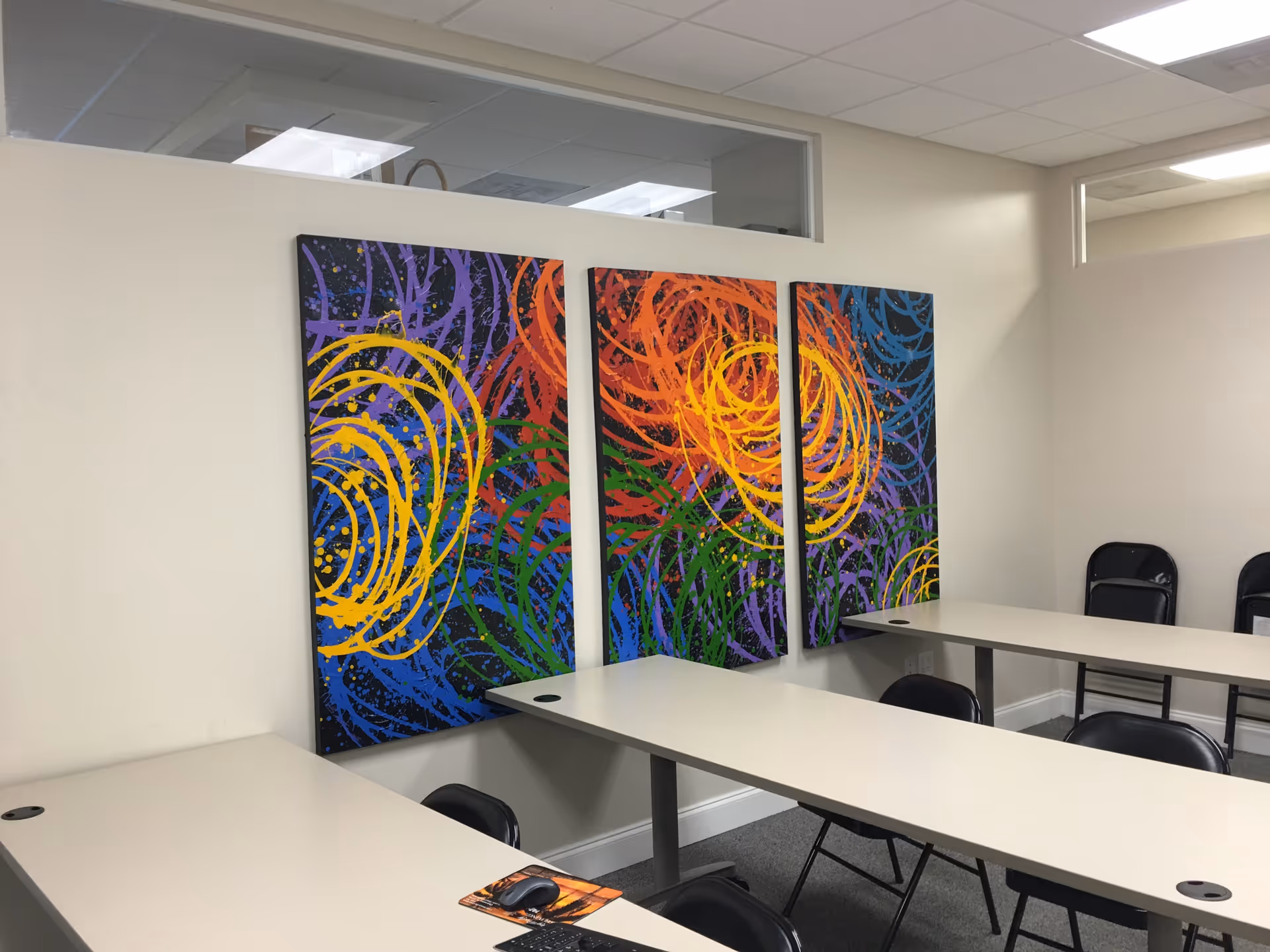 Bright interior with white tables, chairs, and colorful three-panel wall art.
