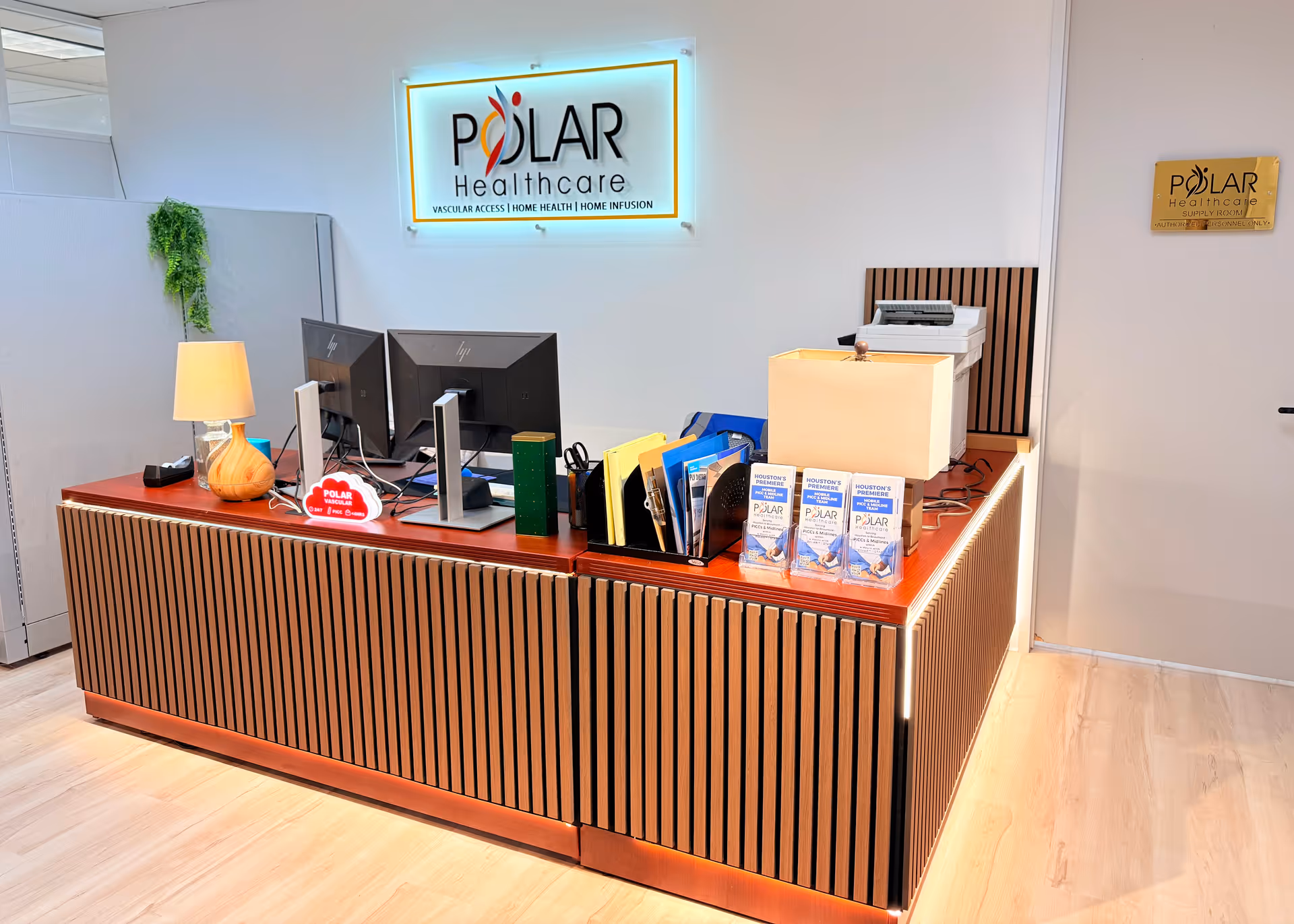 Reception desk in Polar Healthcare with computers, brochures, and illuminated logo sign.