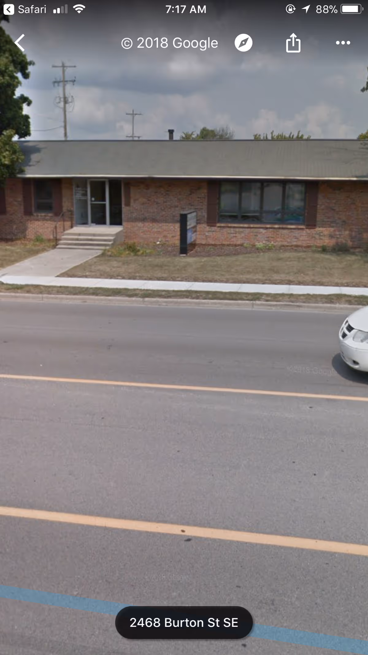 Brick, single-story facility exterior with entrance, windows, and sidewalk along street.