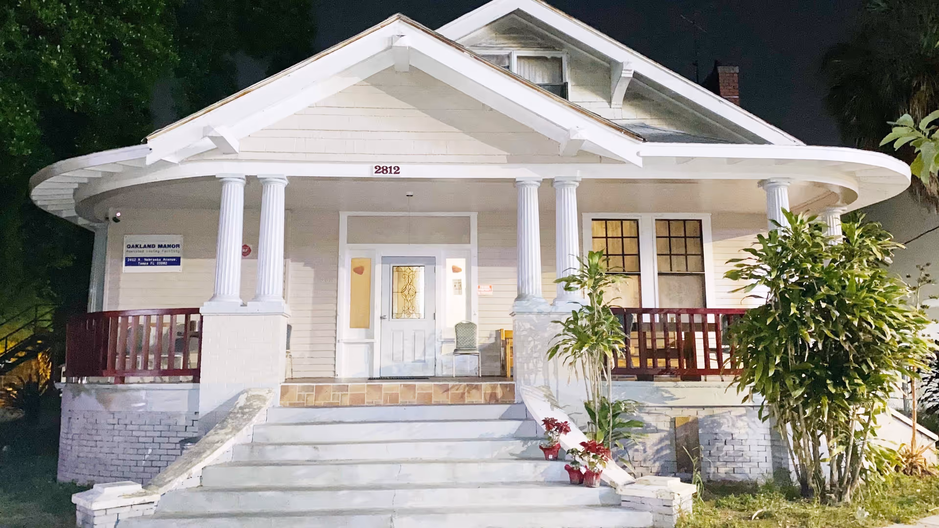 Night exterior of Oakland Manor, a single-story house-style senior living facility with steps and porch.