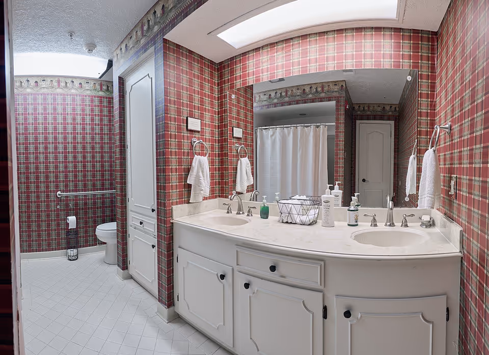 A pink plaid bathroom with a double sink vanity and shower curtain.