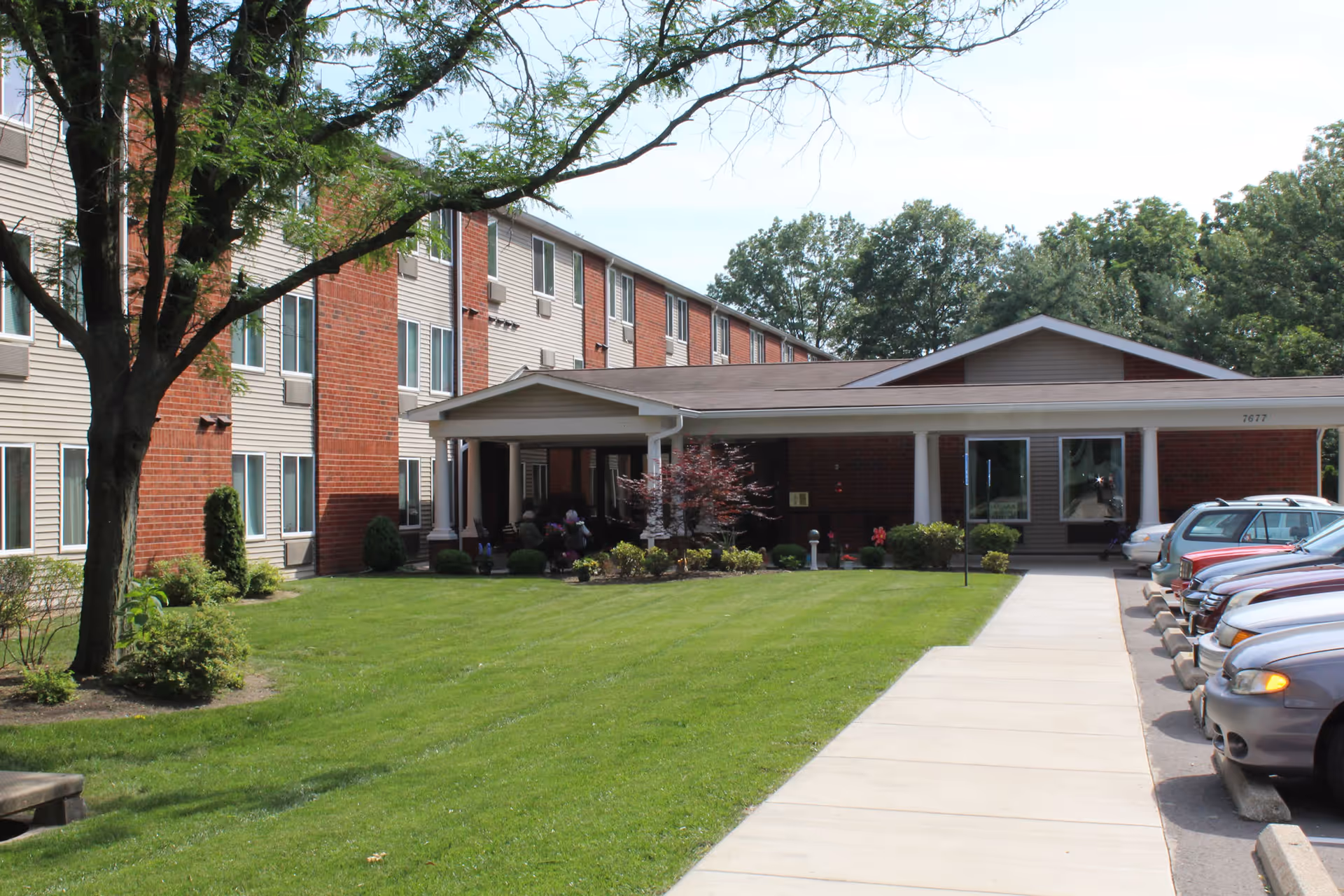 Exterior view of St Josephs Apartments: brick building, green lawn, and parking along the sidewalk.