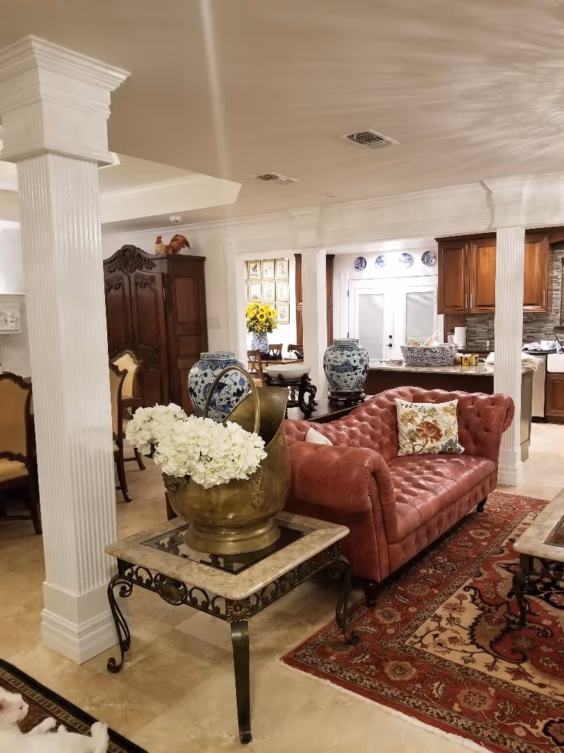 Luxurious living area with a red tufted sofa, ornate furnishings, and floral decor.