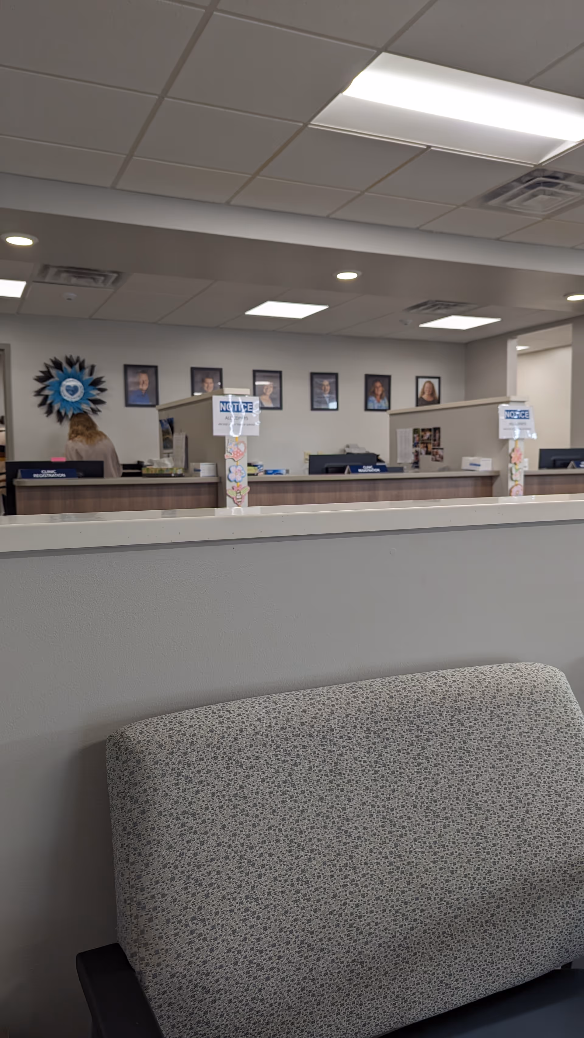 Interior of a medical center lobby with a long reception desk and portraits.