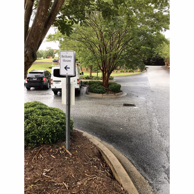Exterior driveway with a Bethany House sign, trees, and parked cars near the entrance.