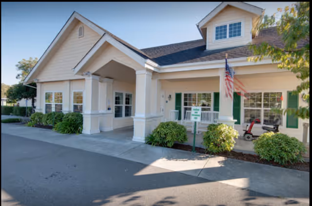 Exterior view of Sequoia Springs Senior Living Community building with front entrance and flag.