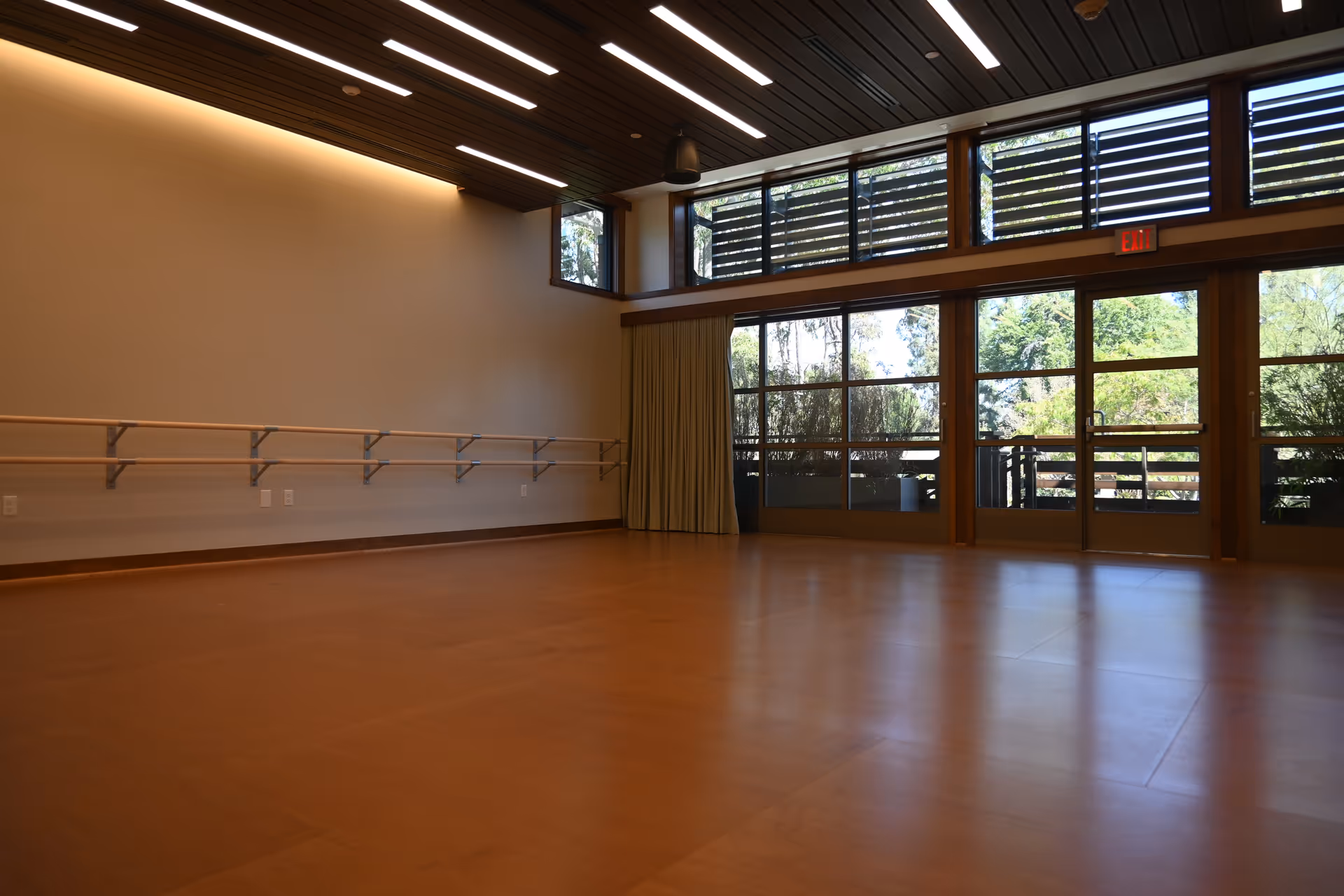 Spacious indoor recreation room with a ballet barre, wooden floor, and large glass doors.