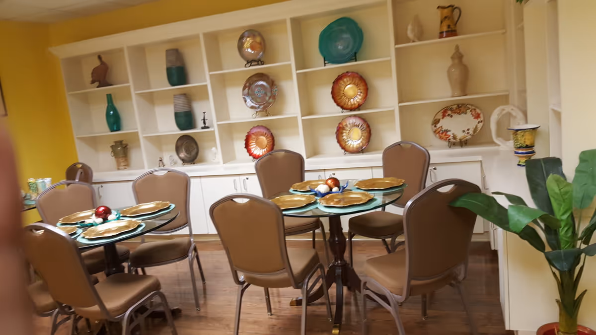 A dining room with round tables set with plates and tan chairs.