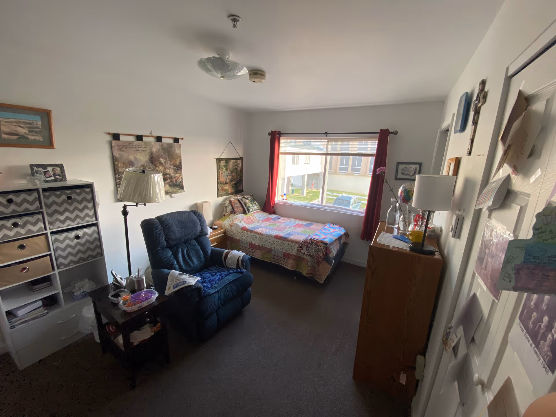 Cozy bedroom in a senior living unit with a bed, recliner, and dresser.