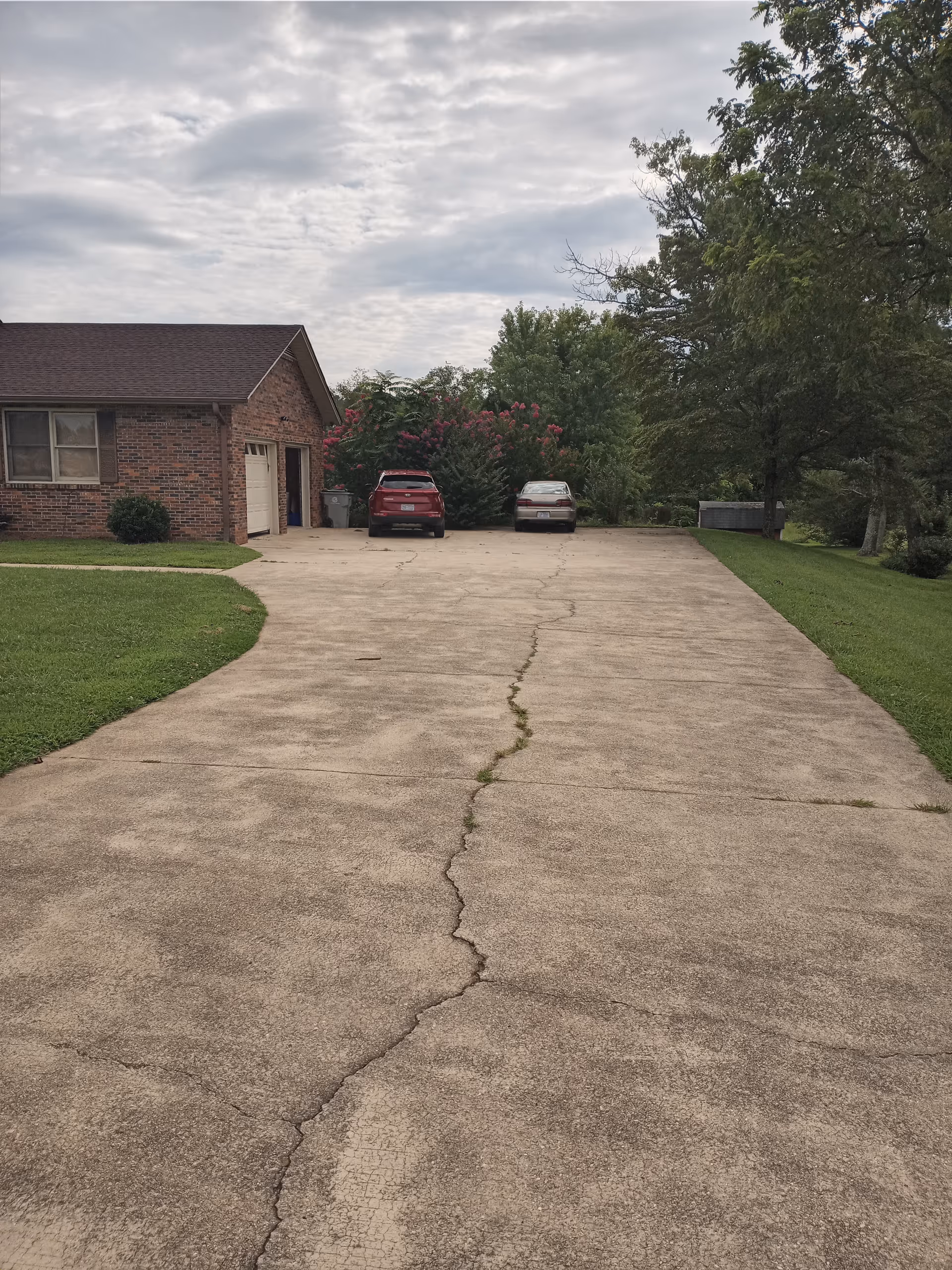Cracked concrete driveway leads to TLC Family Care Home, a brick building with parked cars.