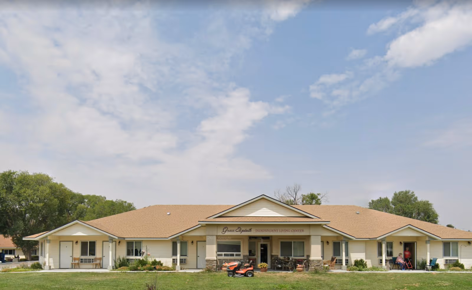 Grace Mountain Home front exterior: a single-story beige facility with a central entrance and people nearby.