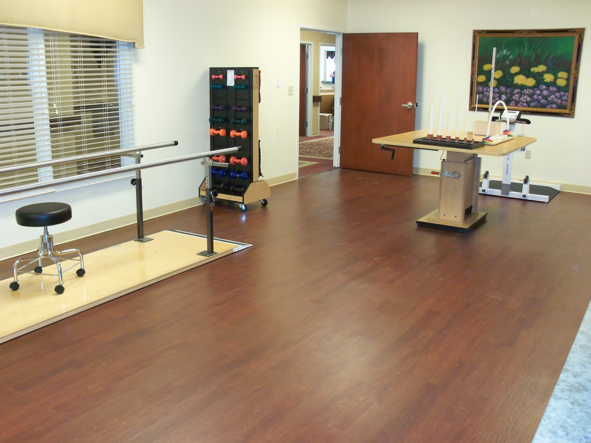 Therapy room with parallel bars, a weights rack, and a therapy table.