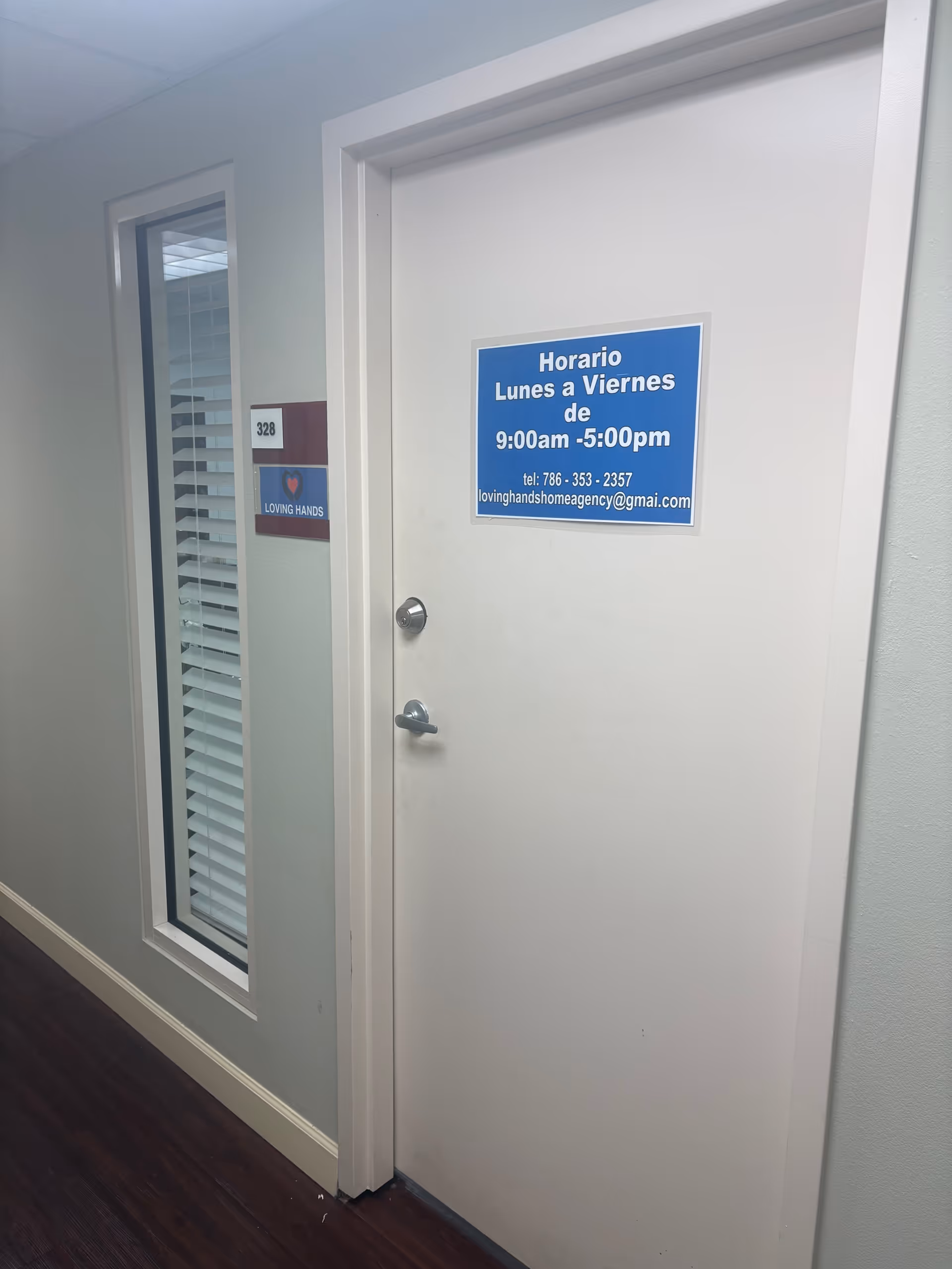 Interior hallway featuring a closed white door with blue sign and window with blinds.