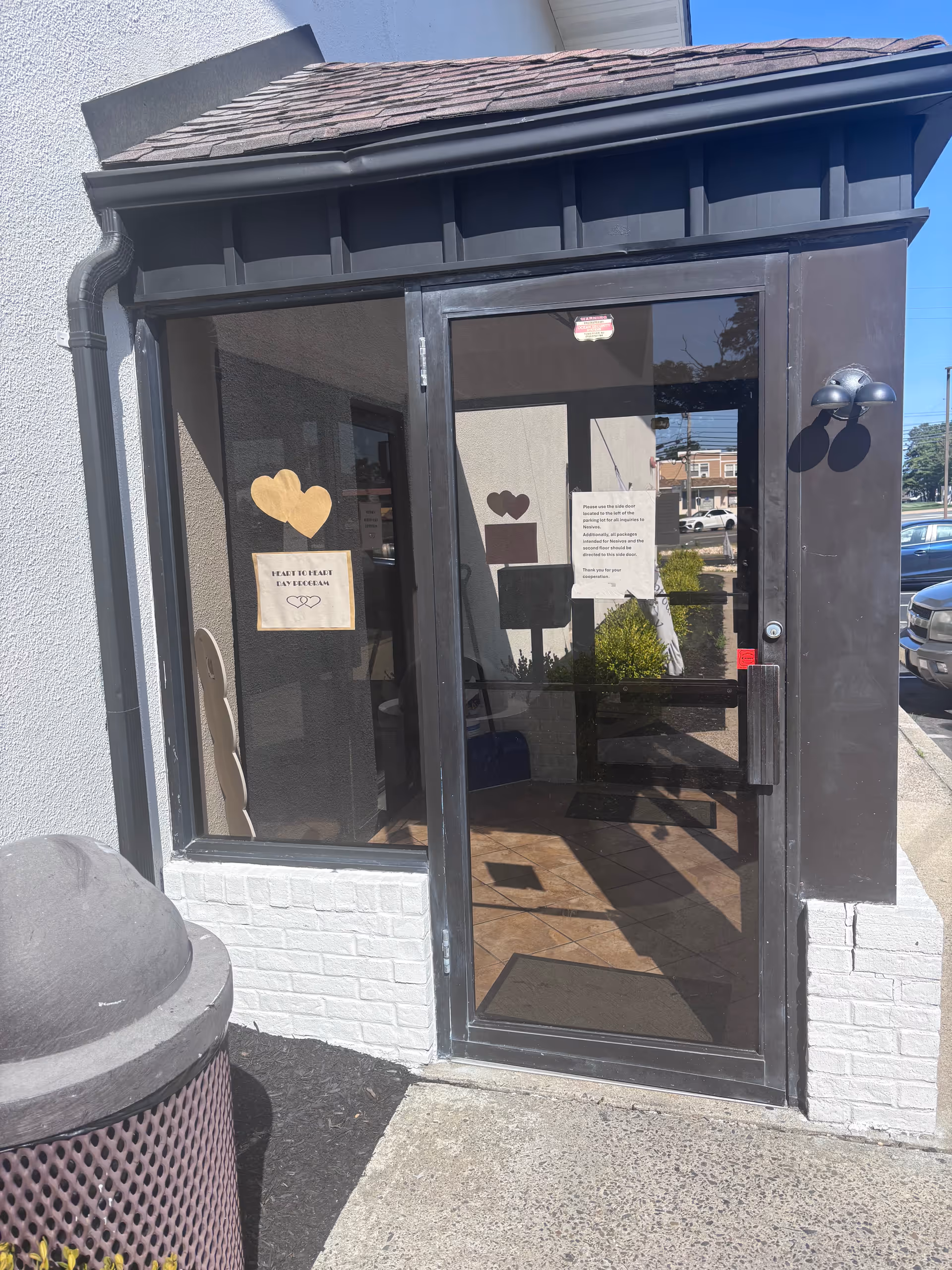 Glass entrance door with heart stickers and signs at Heart to Heart Adult Day Program.