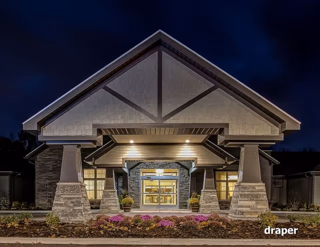 Nighttime exterior view of Maplewood at Cuyahoga Falls entrance with lit facade and landscaping.