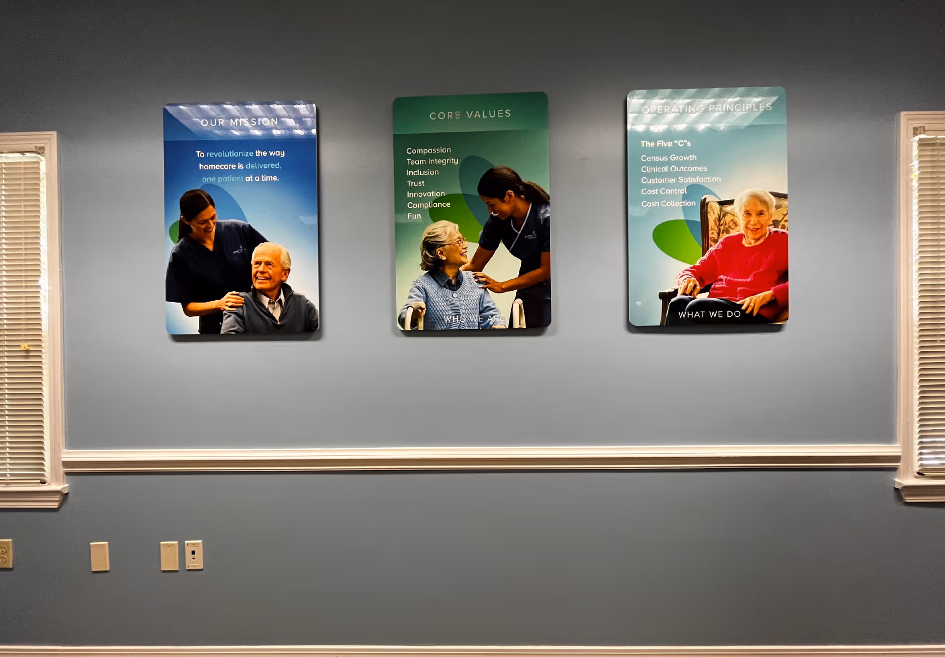 Blue-gray wall featuring three posters of elderly people and a caregiver.