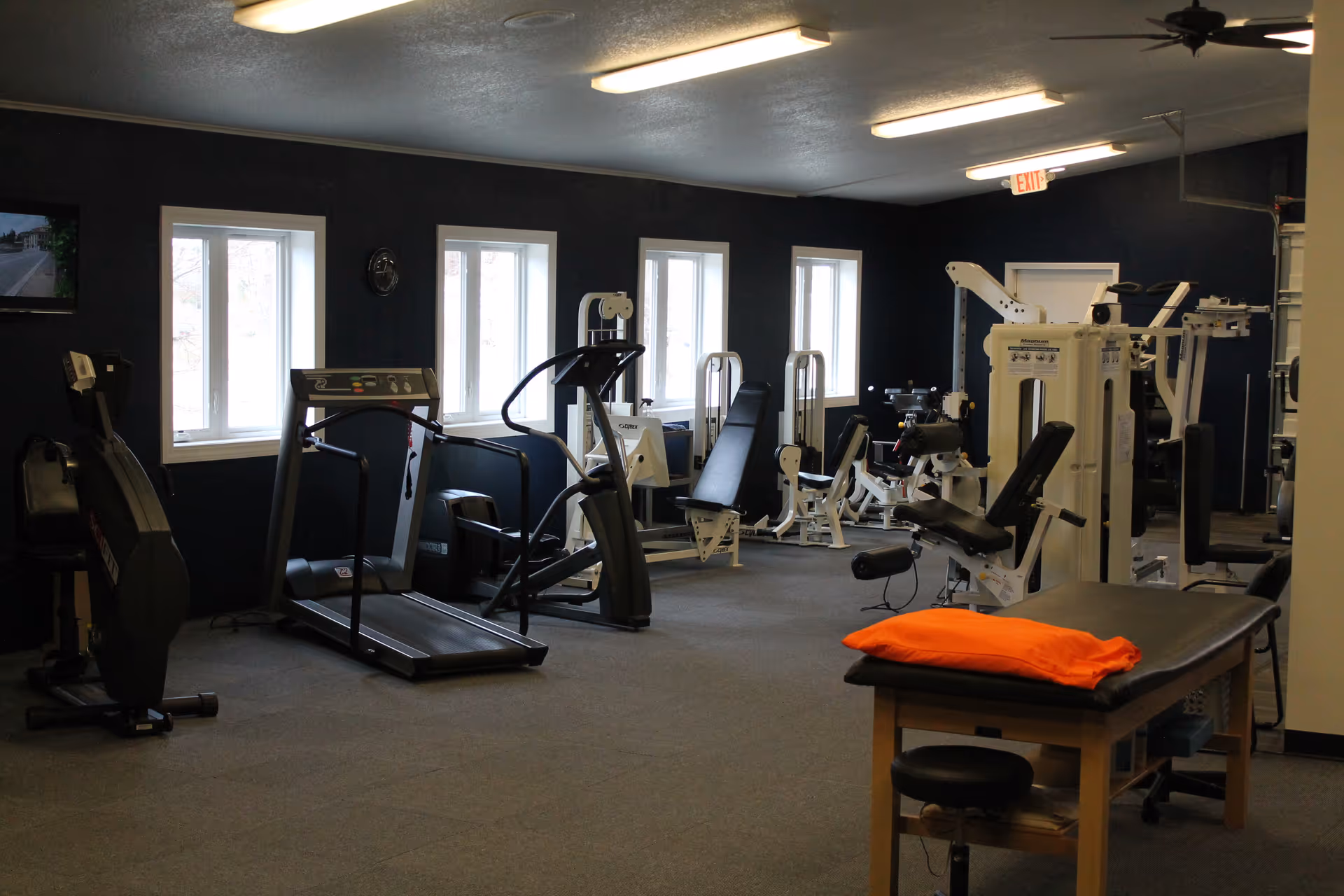 A rehabilitation gym inside a facility with treadmills, weight machines, and a therapy table.