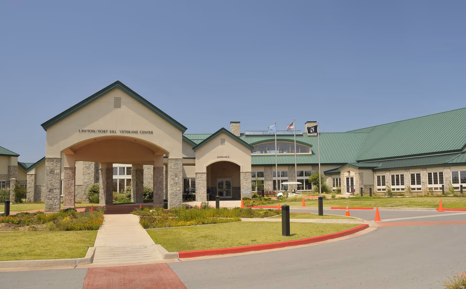 Exterior view of a veterans center with green roof, arched entrance, and landscaping.