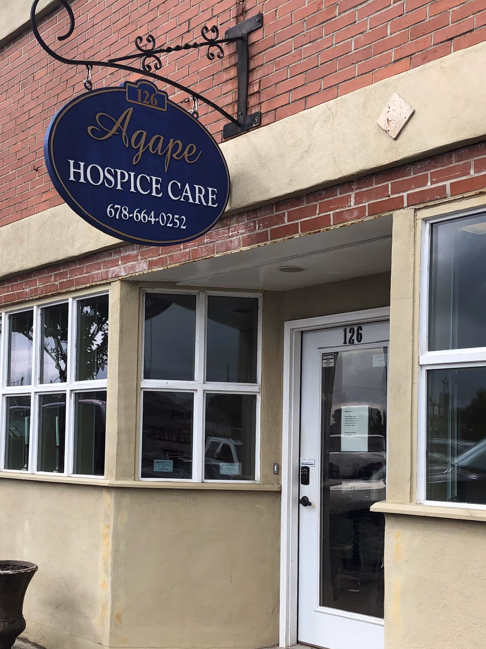 Exterior view of Agape Hospice Care sign and doorway on brick building
