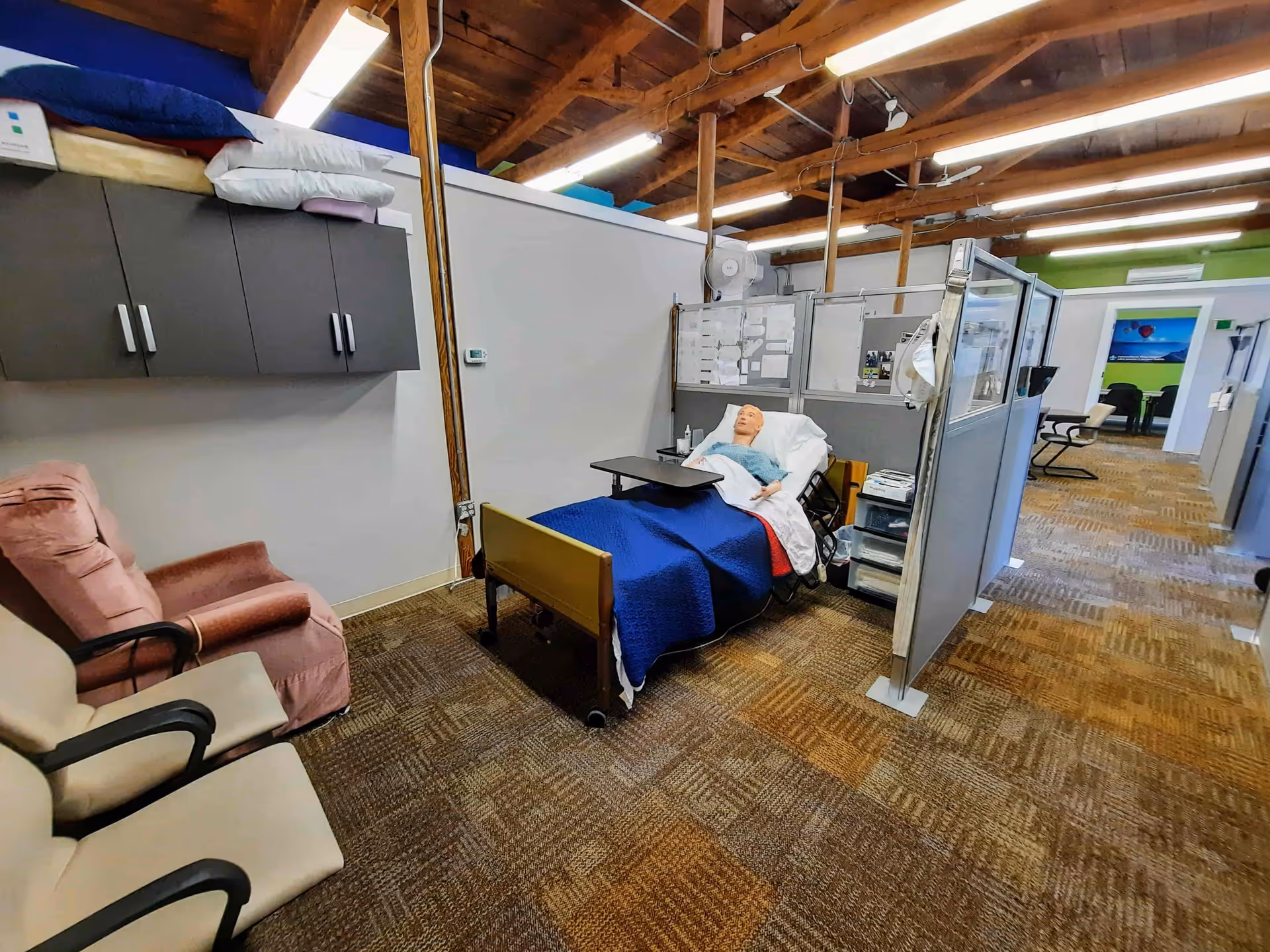 Hospital bed in a cubicle-style care training area inside a senior facility.
