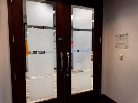 Double glass doors with frosted panels in a hallway near room 110