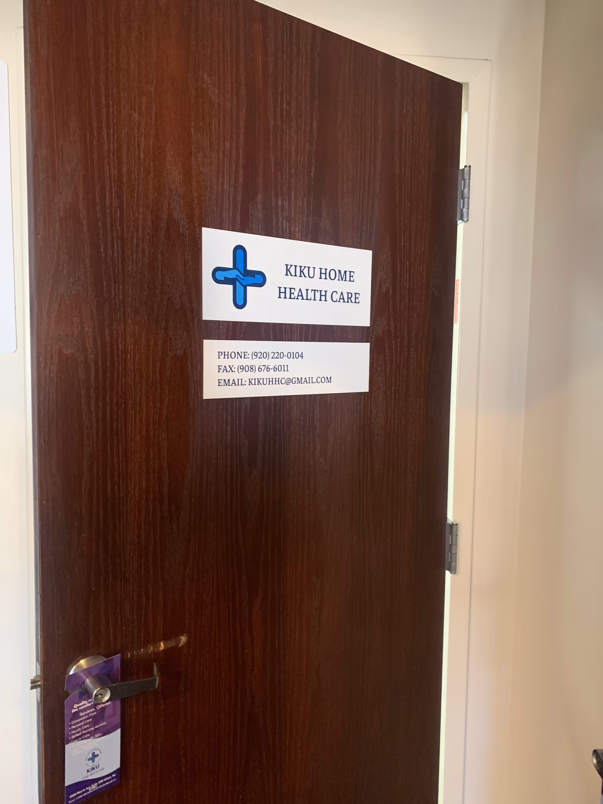 Wooden interior door with a Kiku Home Health Care sign and contact information.