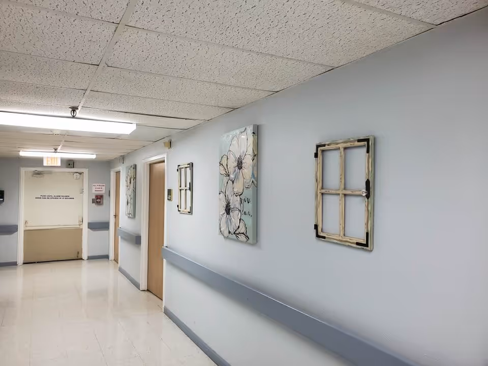 A long, empty hallway in a senior care facility with blue walls and wall art.