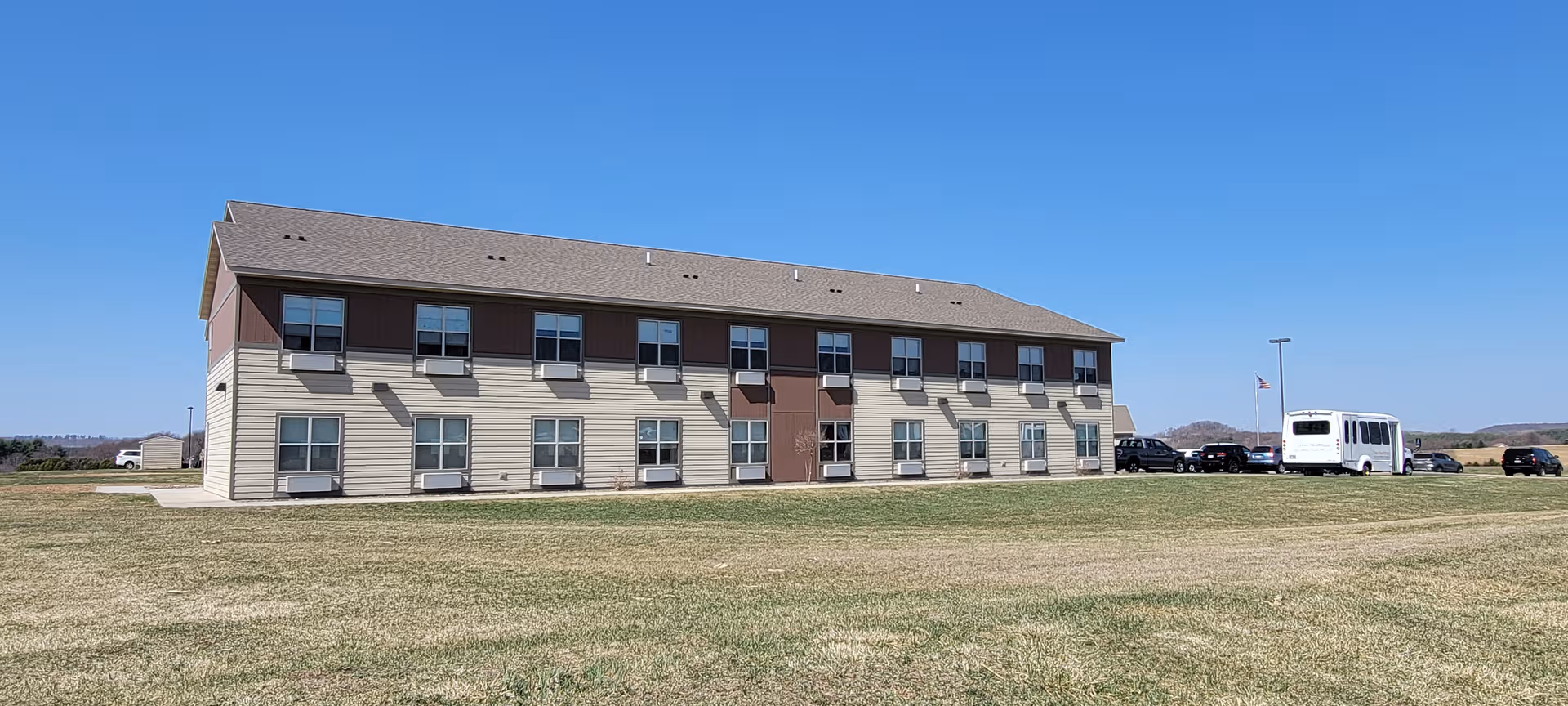 Front view of Dove Healthcare Osseo Assisted Living, a two-story building with parked vehicles.