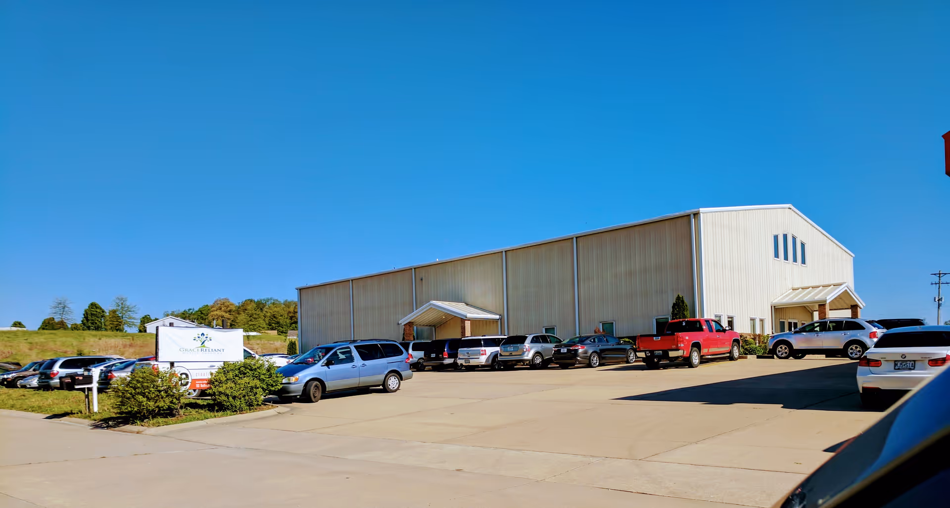 Exterior view of a beige building with a parking lot full of cars and blue sky.