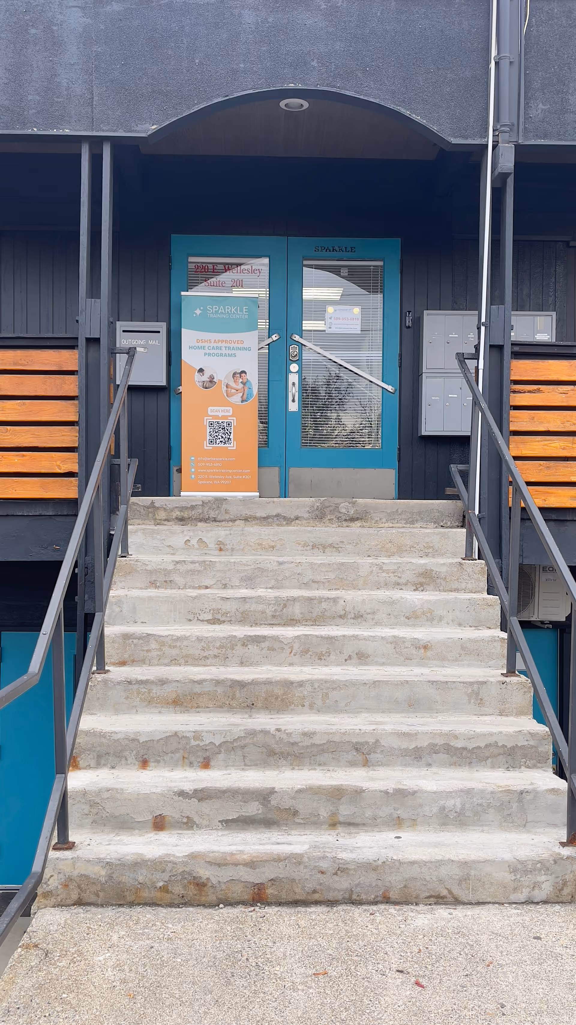 Exterior view of Sparkle Training Center entrance with teal door and steps.