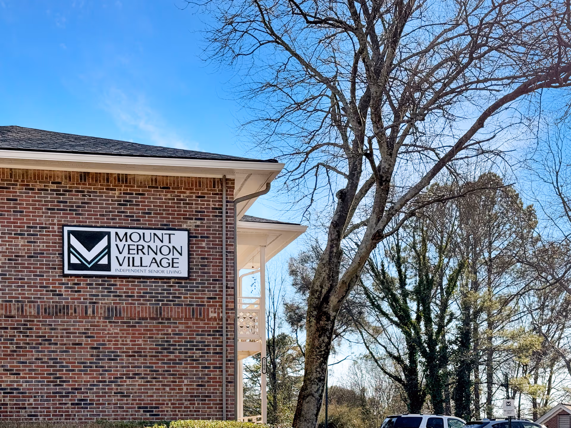 Brick building with Mount Vernon Village sign and leafless trees outside on a sunny day