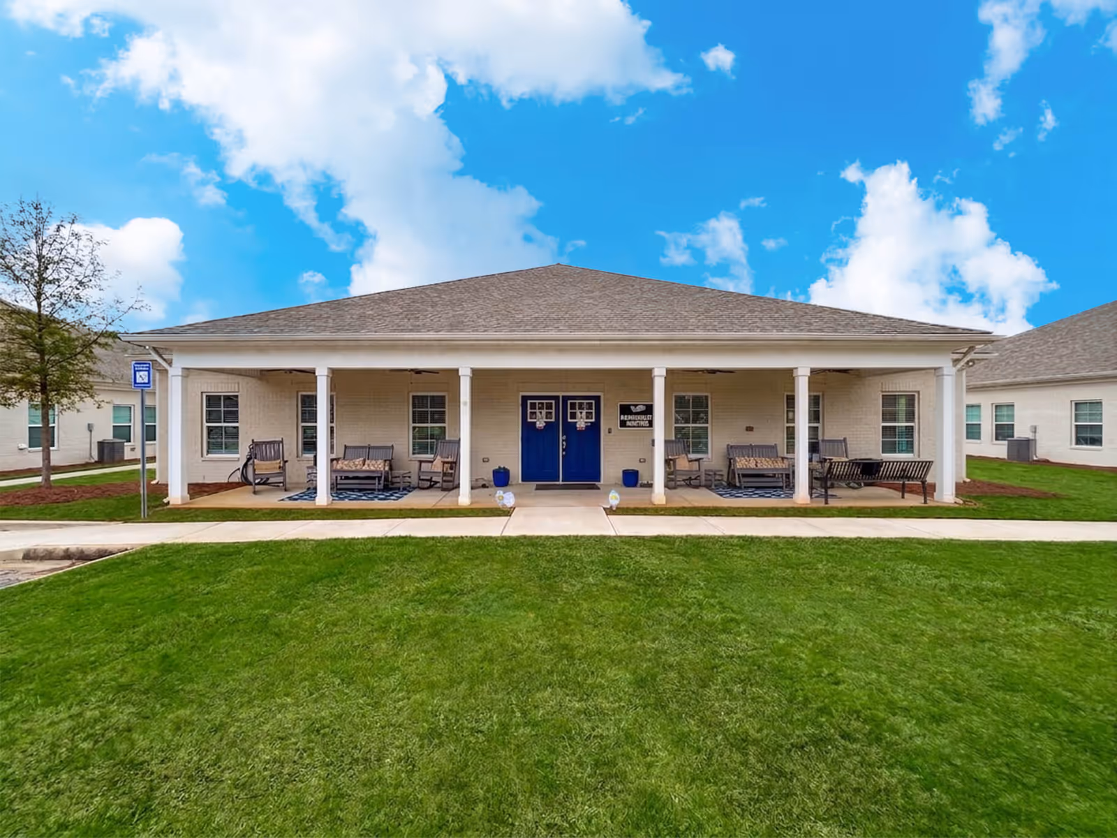 Front view of The Landing Senior Living building with blue doors and porch seating.