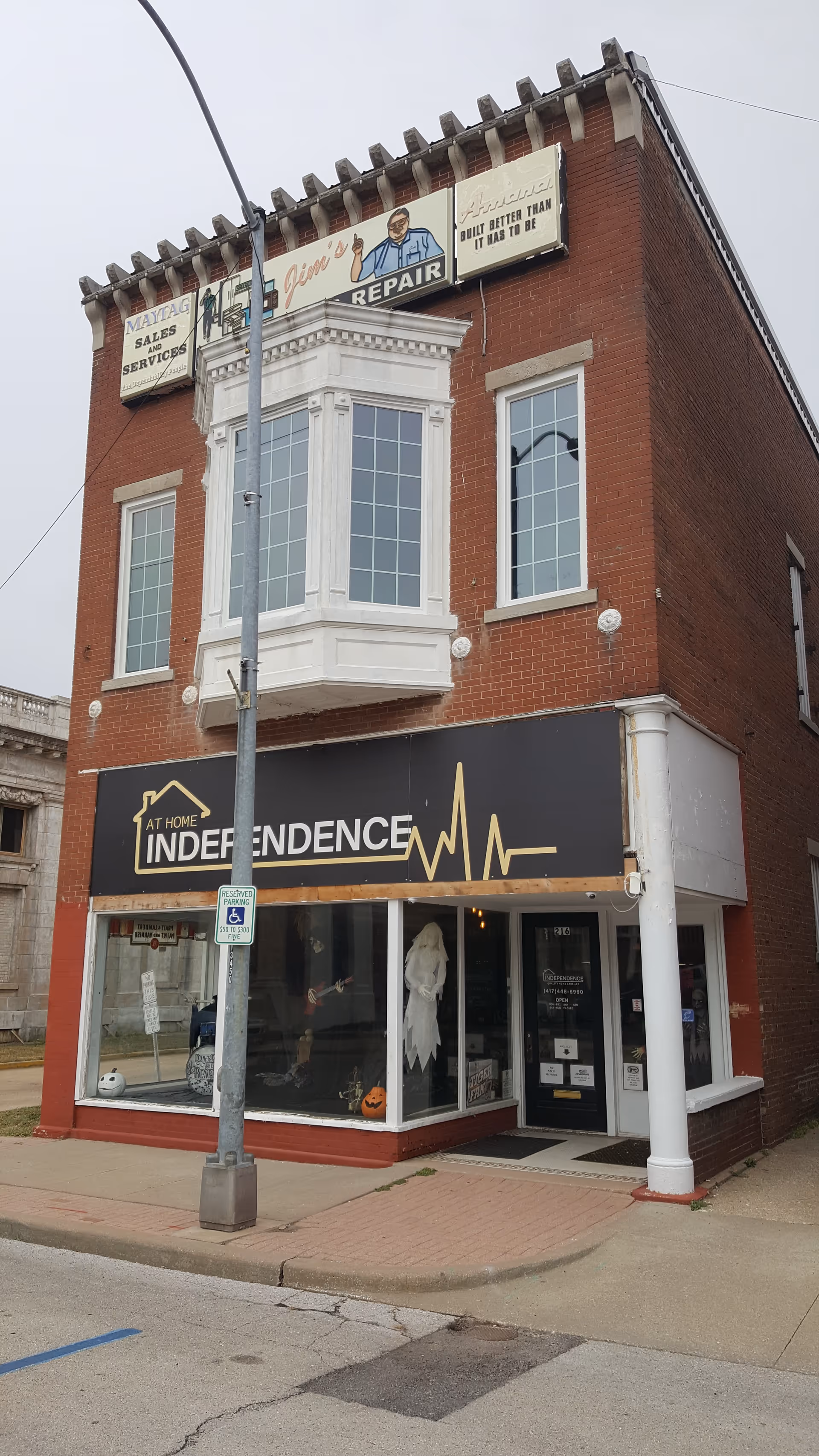 Brick two-story building with a storefront sign reading 'At Home Independence' on the ground floor.