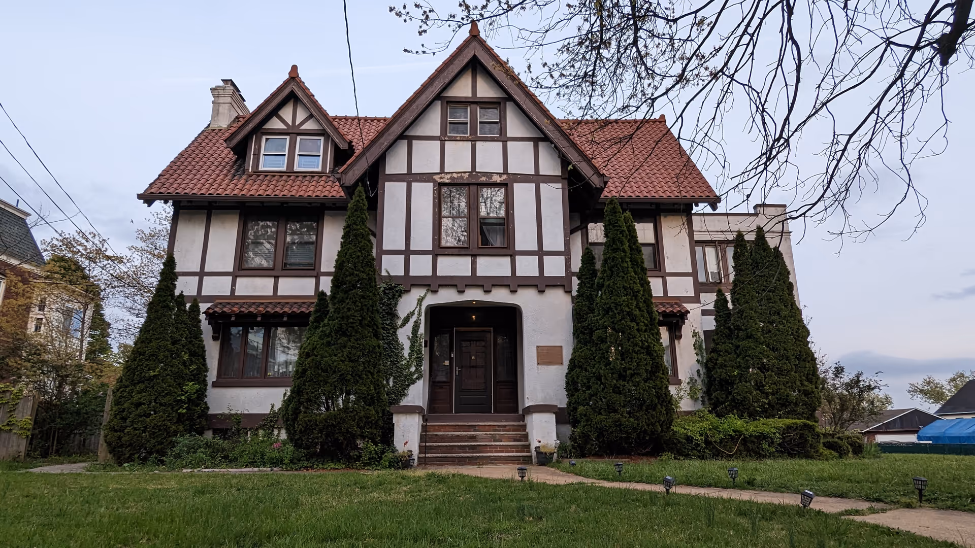 Exterior view of Boyd House, Tudor-style building with central entrance and tall evergreen trees.