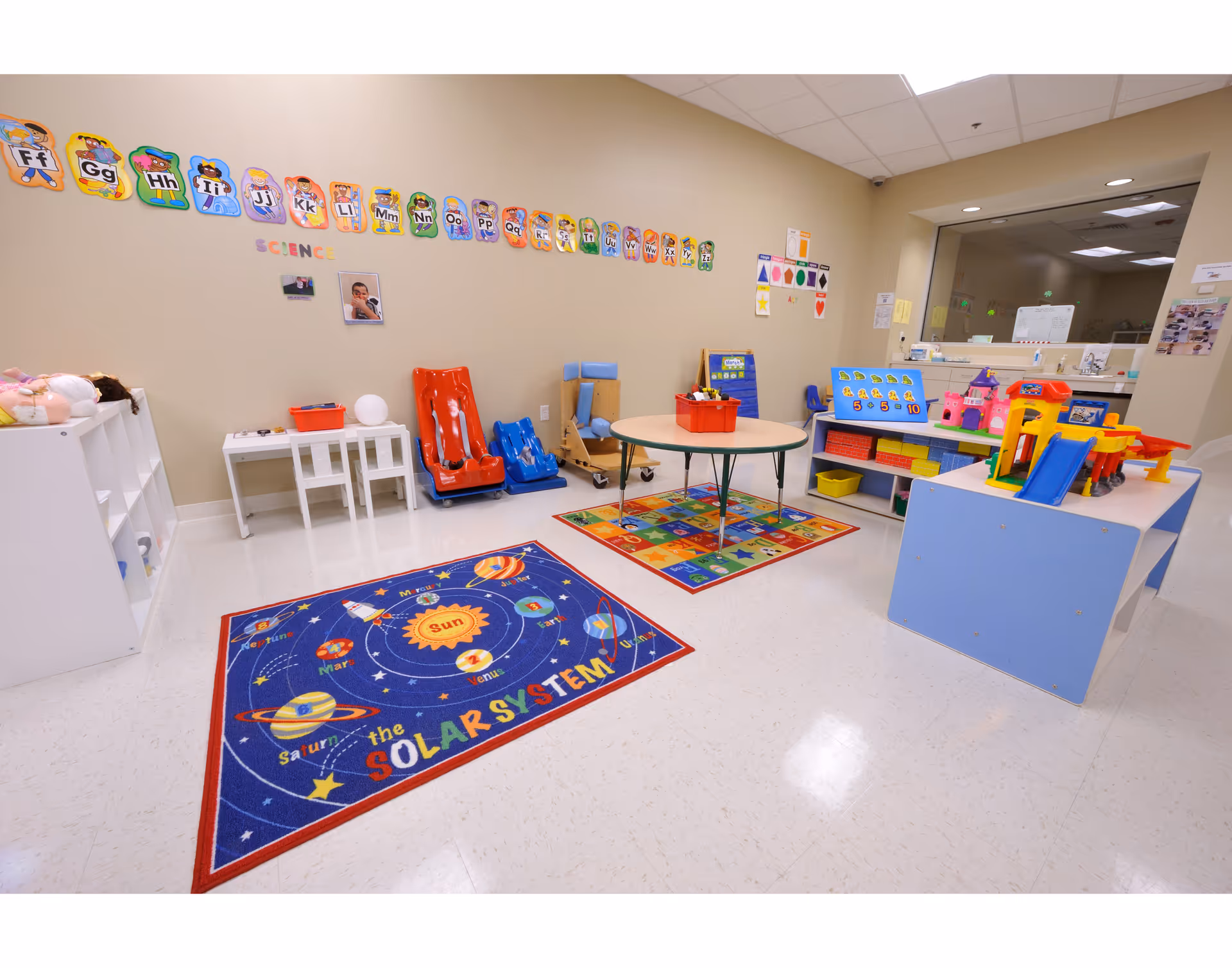 Bright children's playroom with colorful rugs, toys, and a round table in a senior living facility.